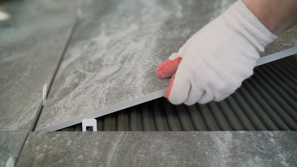 a person is laying a tile on the floor .