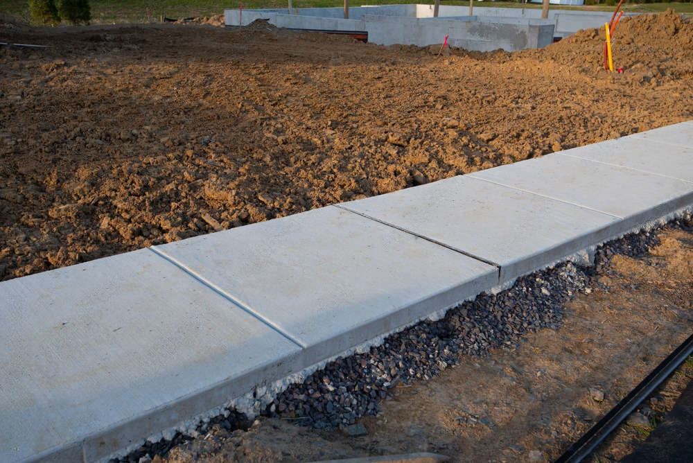 a concrete sidewalk is being built in a dirt field