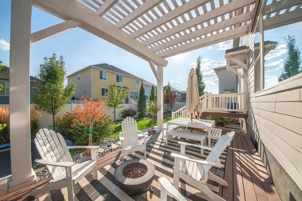 a patio with chairs , a table and a fire pit under a pergola .
