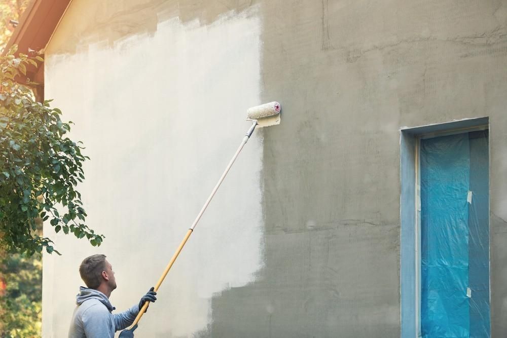 a man is painting a wall with a paint roller .
