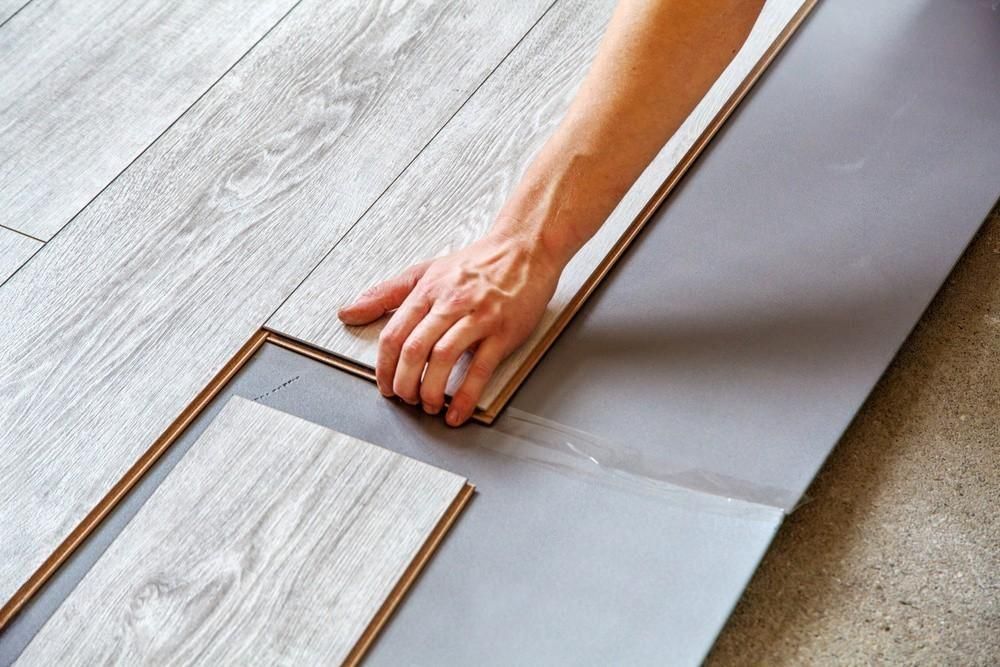 a person is installing a wooden floor in a room .