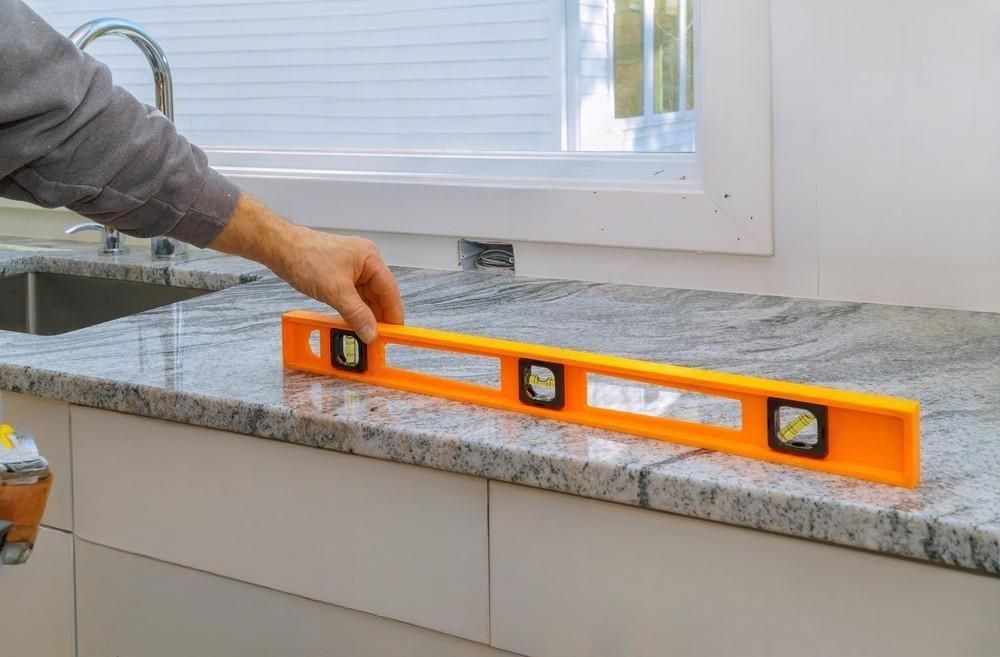 a person is measuring a granite counter top with a level .