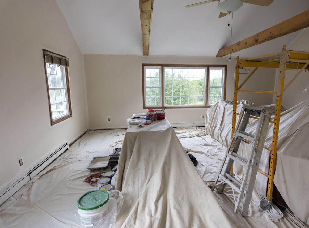 a room that is being painted with a ladder and buckets of paint .