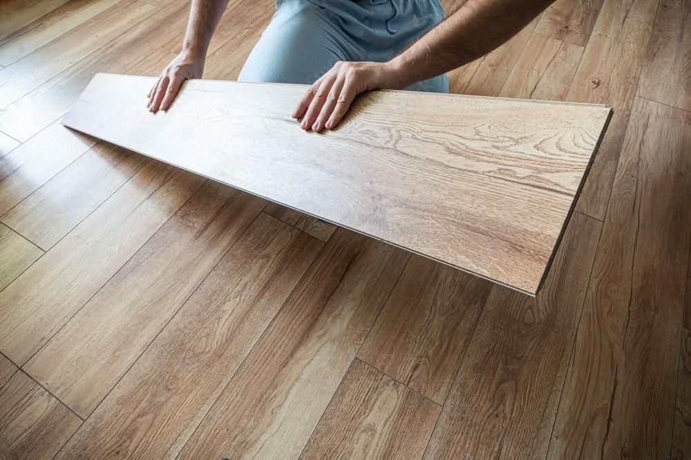 a person is kneeling on the floor holding a piece of wood .