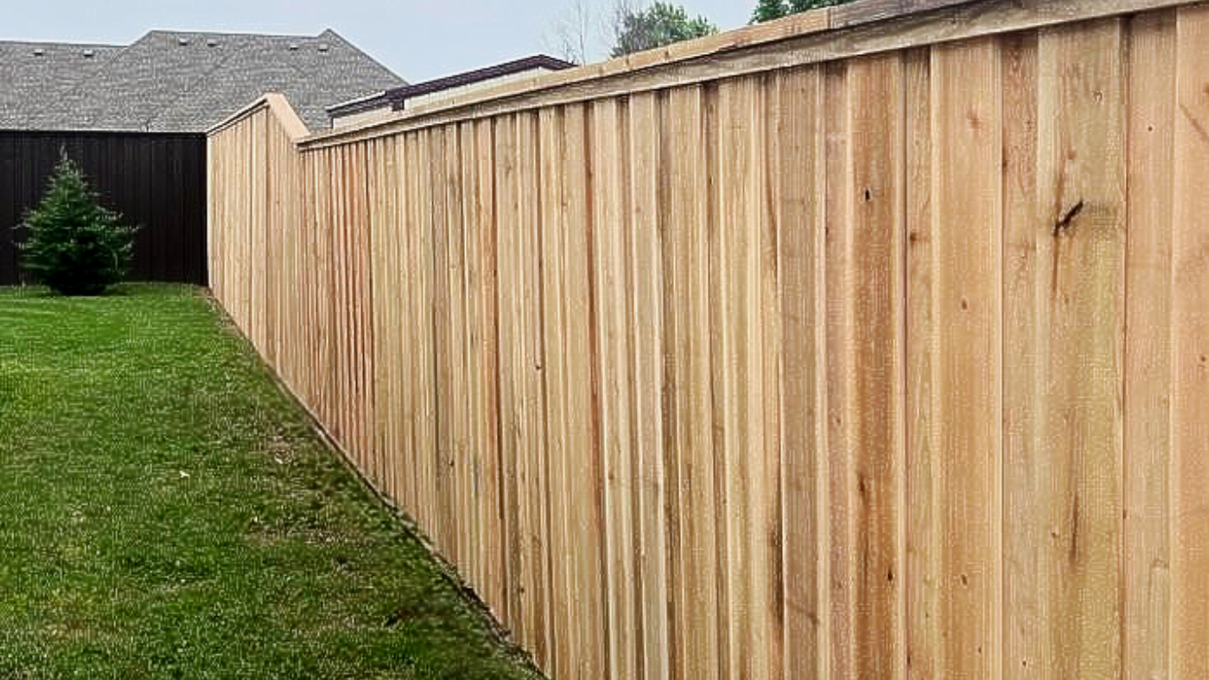 Wooden fence bordering green lawn, overcast sky in background.
