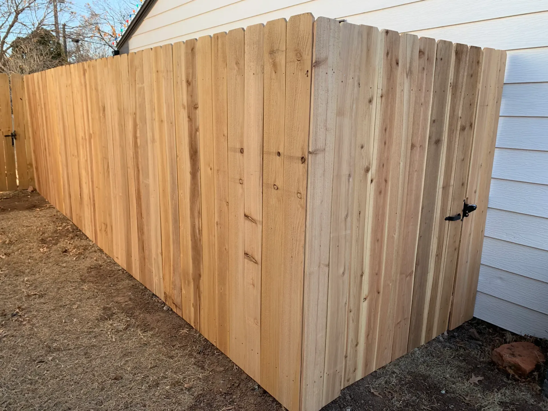 A wooden fence is sitting in front of a white house.