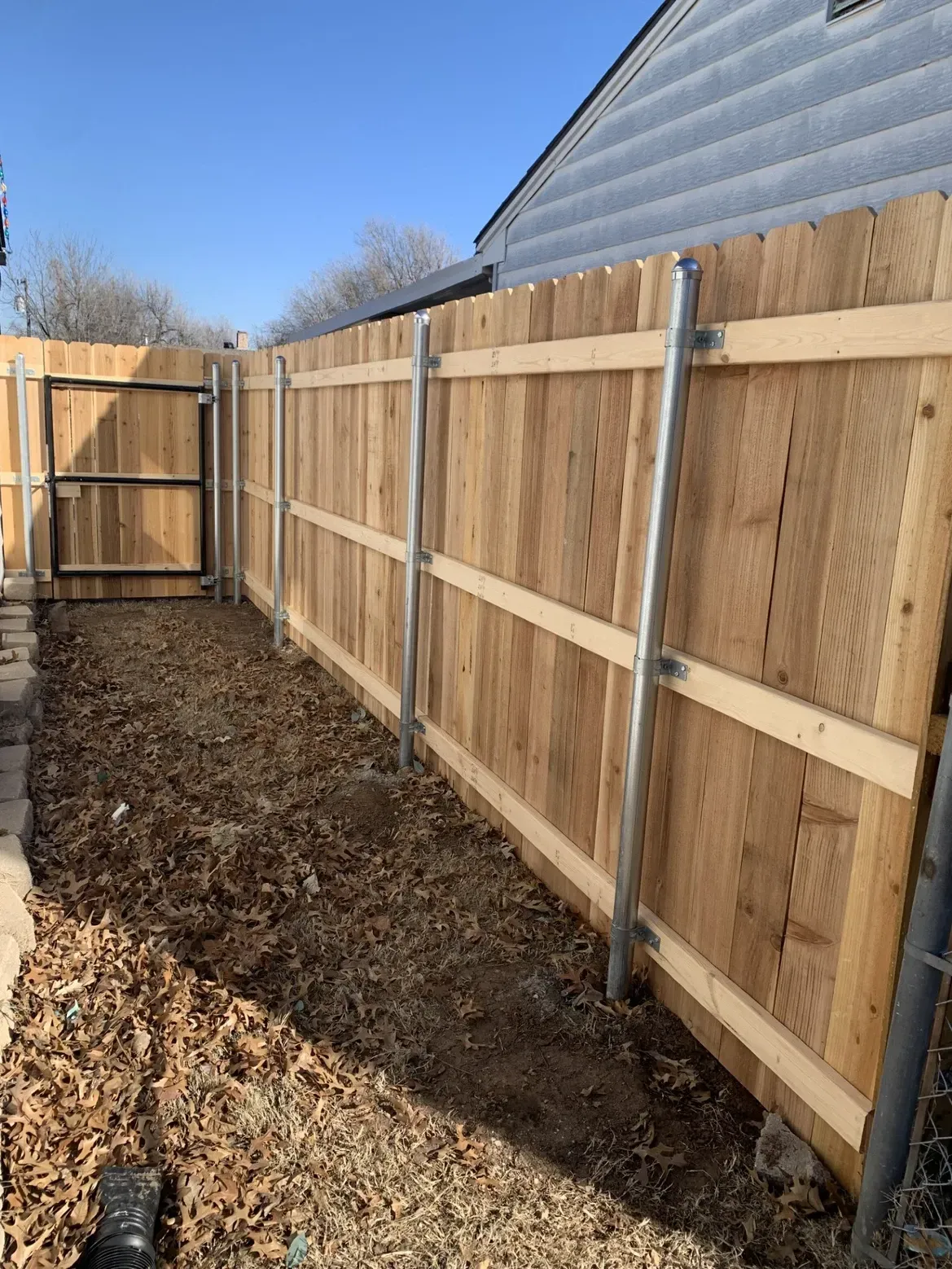 A wooden fence with a gate in the backyard of a house.