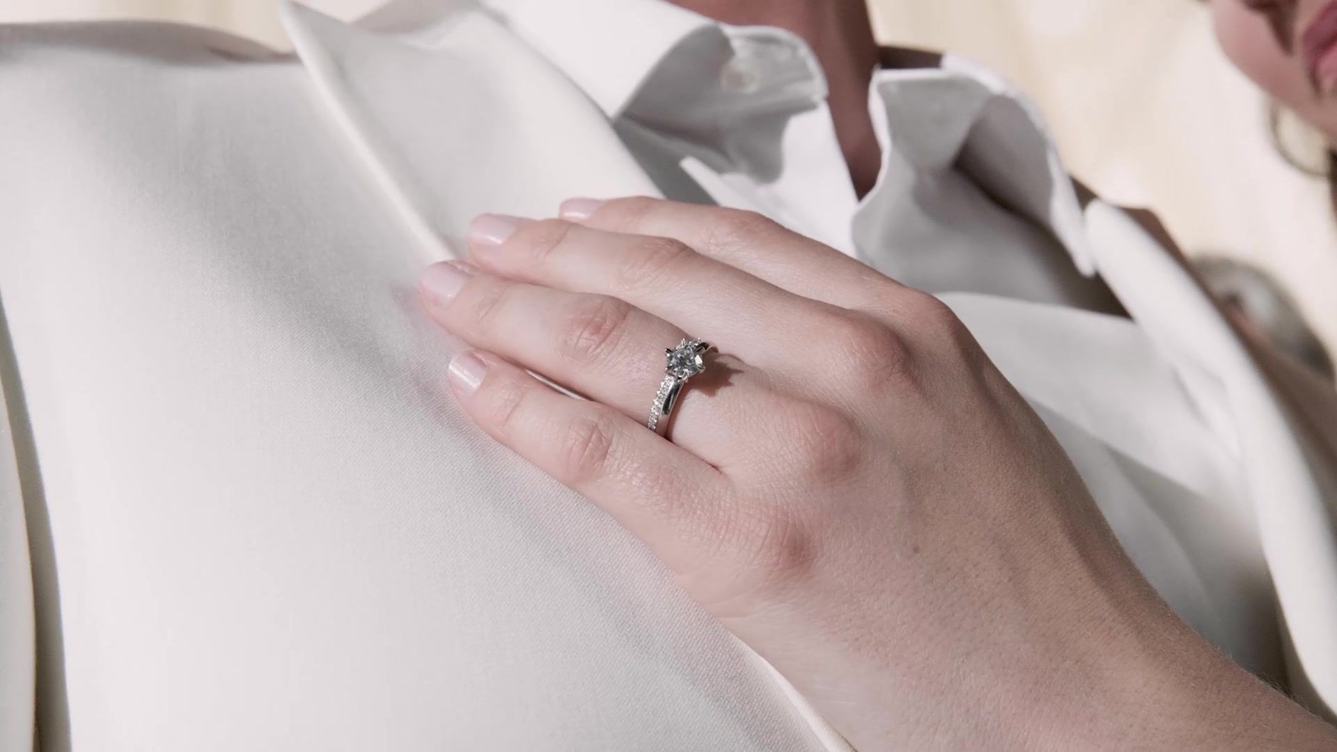 Hand met diamanten ring op een bruidsjurk