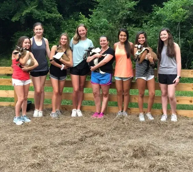A group of girls standing next to each other holding goats