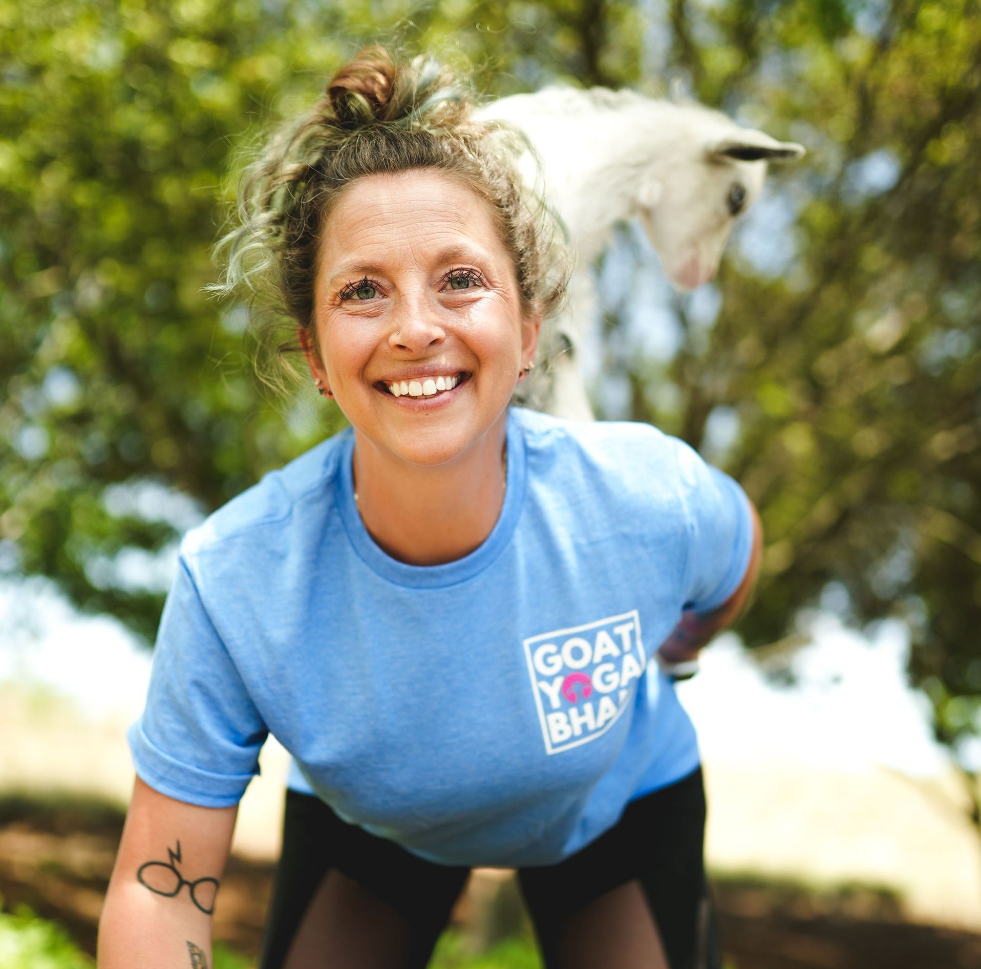 A woman wearing a blue shirt that says goat yoga on it