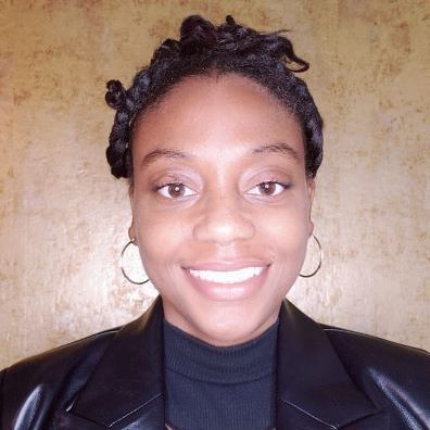 A woman wearing a black jacket and earrings is smiling for the camera.