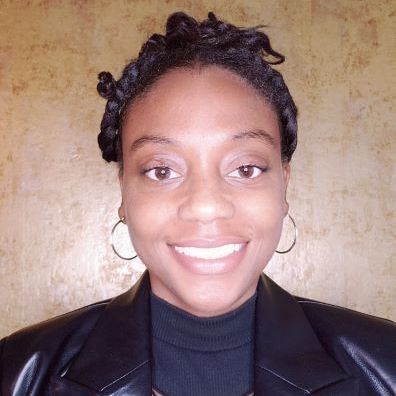 A woman wearing a black jacket and earrings is smiling for the camera.