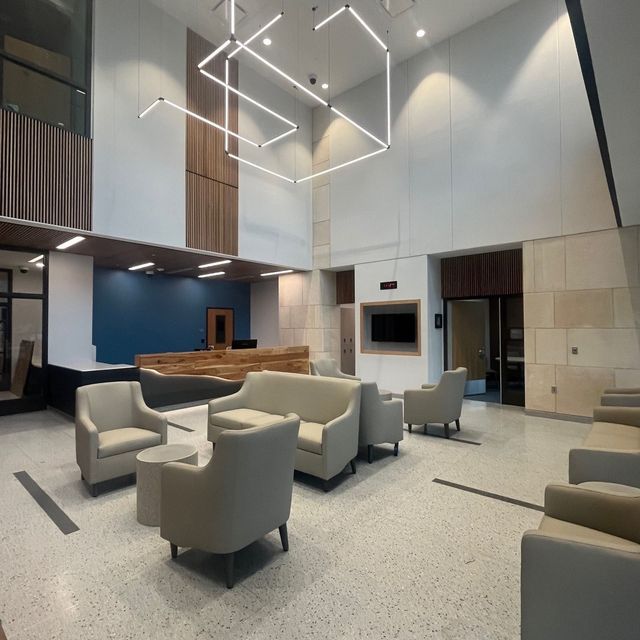 Modern hotel lobby with beige lounge chairs, high ceilings, and geometric pendant lights