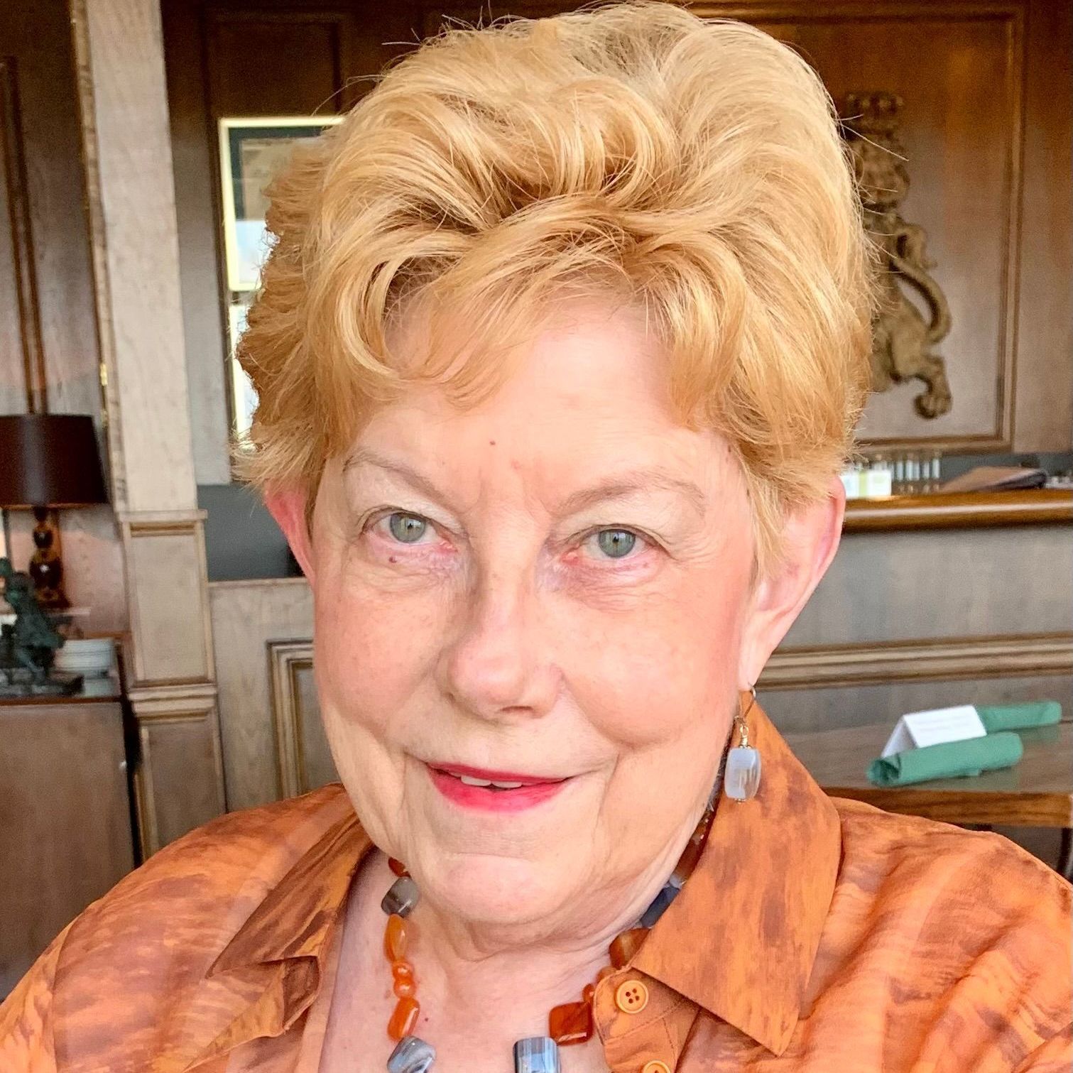 A woman with blonde hair and a necklace is smiling for the camera