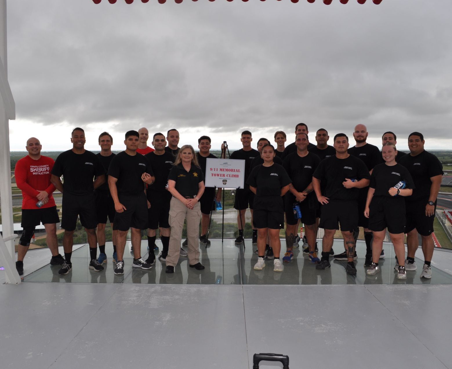 Group of people in black shirts and shorts on a platform, with a sign that says 