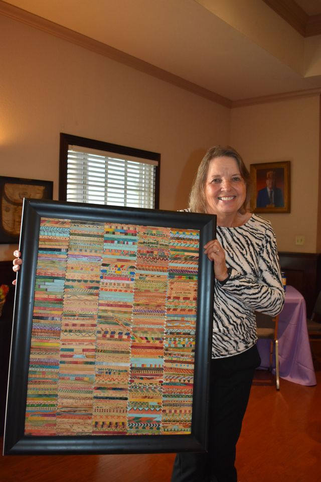 Woman holding framed colorful textile artwork indoors