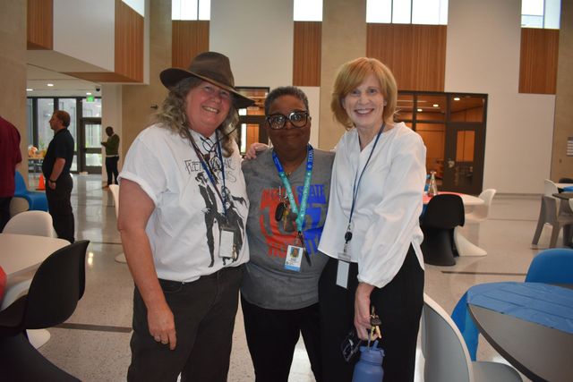 Three people standing together in a bright lobby, smiling at the camera.