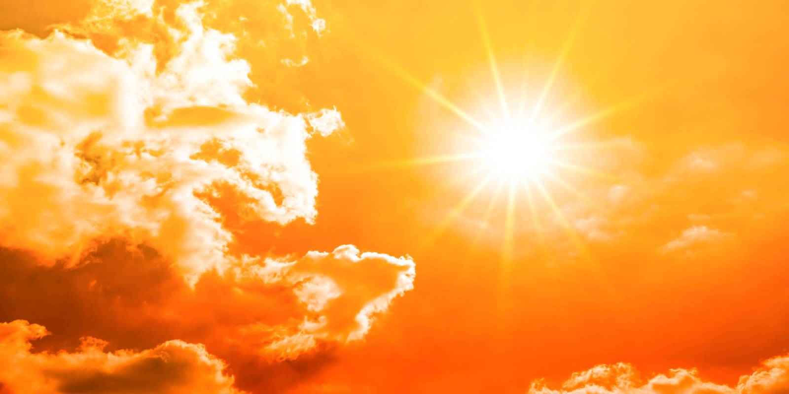 Bright orange sky with a glowing sun and scattered clouds