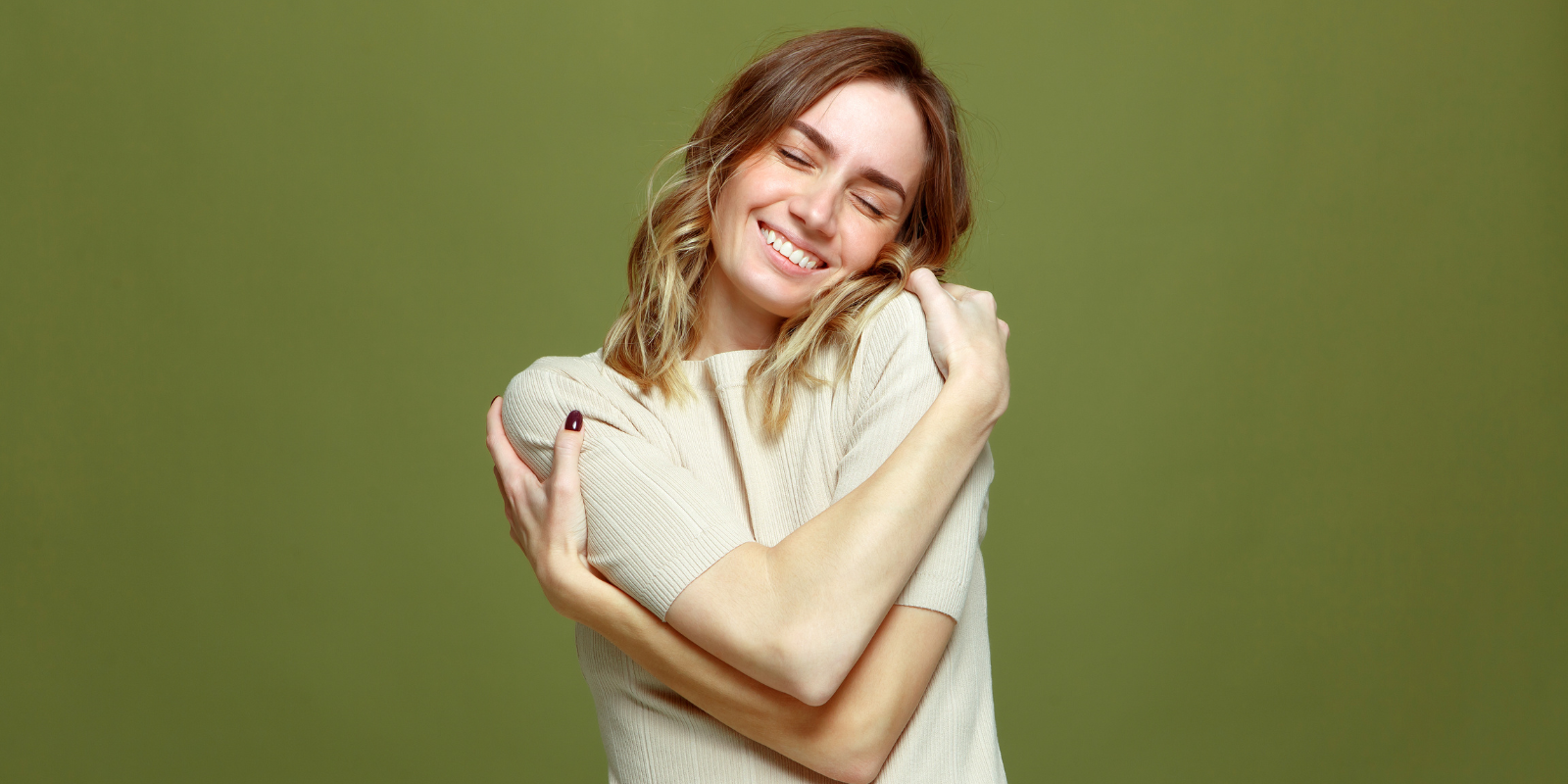 Mental health professional smiling and giving herself a self-care hug