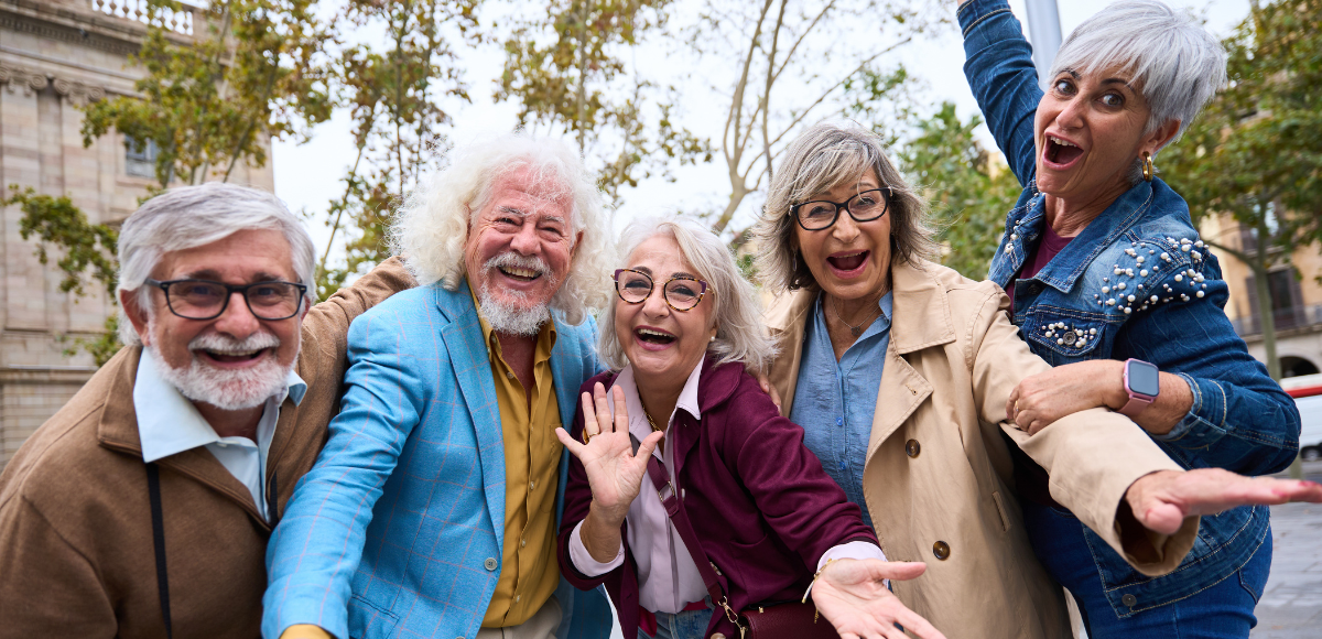 Smiling group of friends outdoors, laughing and leaning toward the camera
