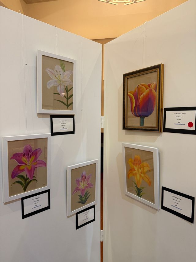Flower paintings displayed on white gallery walls at a corner exhibit
