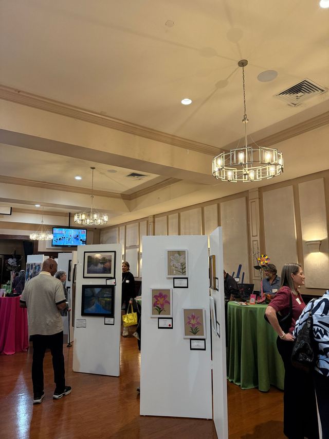 Indoor vendor booth with clothing racks, display panels, and a chandelier in a bright hall