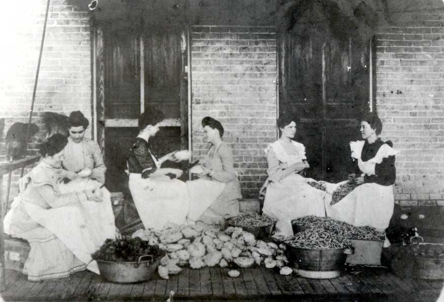 A black and white photo of a group of women sitting on a porch