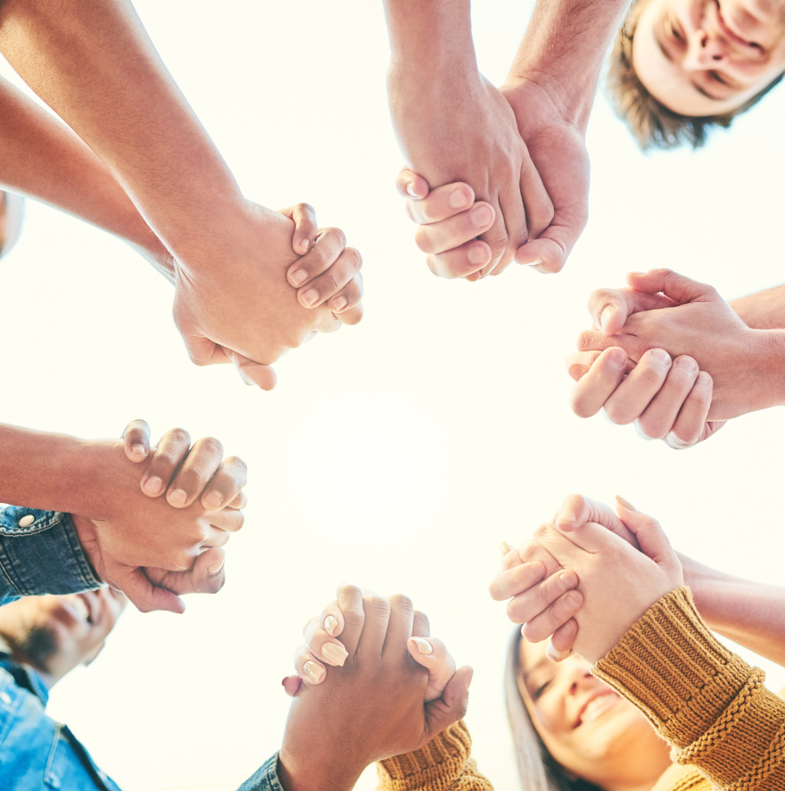 Hands clasped in a circle, viewed from below, suggesting unity and support.