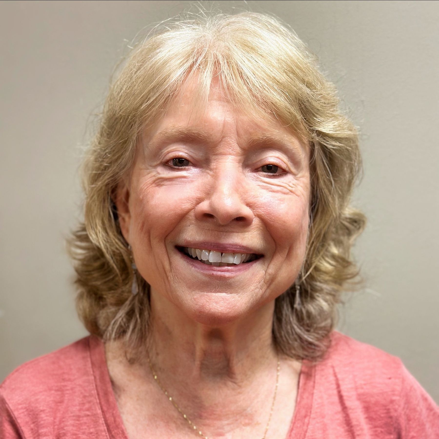 A woman in a red shirt is smiling for the camera.