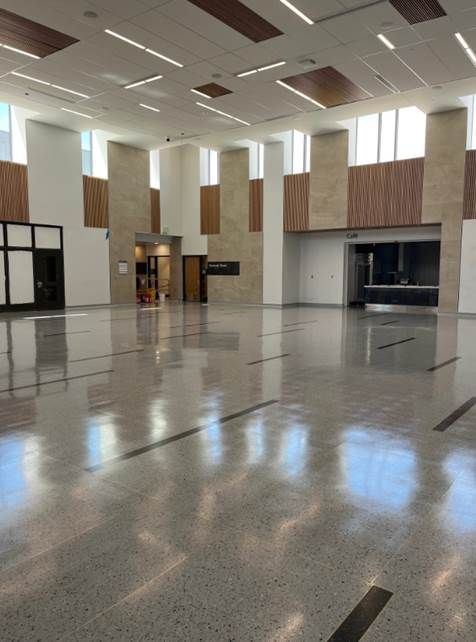 Empty indoor lobby with polished floor, high ceiling, and large wall panels