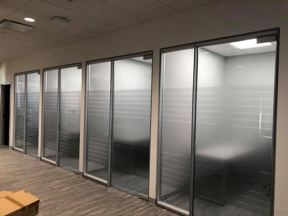 Office hallway with frosted glass conference room partitions and closed doors
