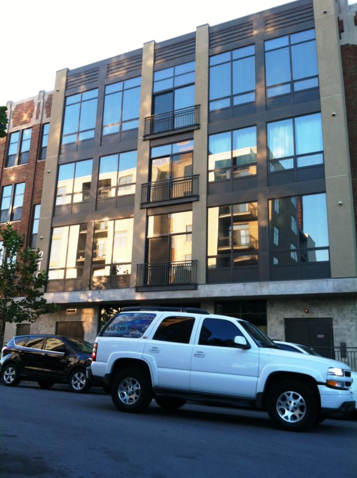 Modern apartment building with reflective windows and parked cars on the street