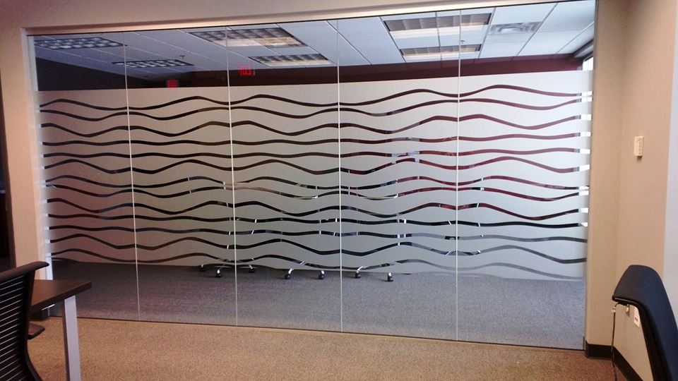 Office interior with frosted glass walls and wavy horizontal lines behind a conference table