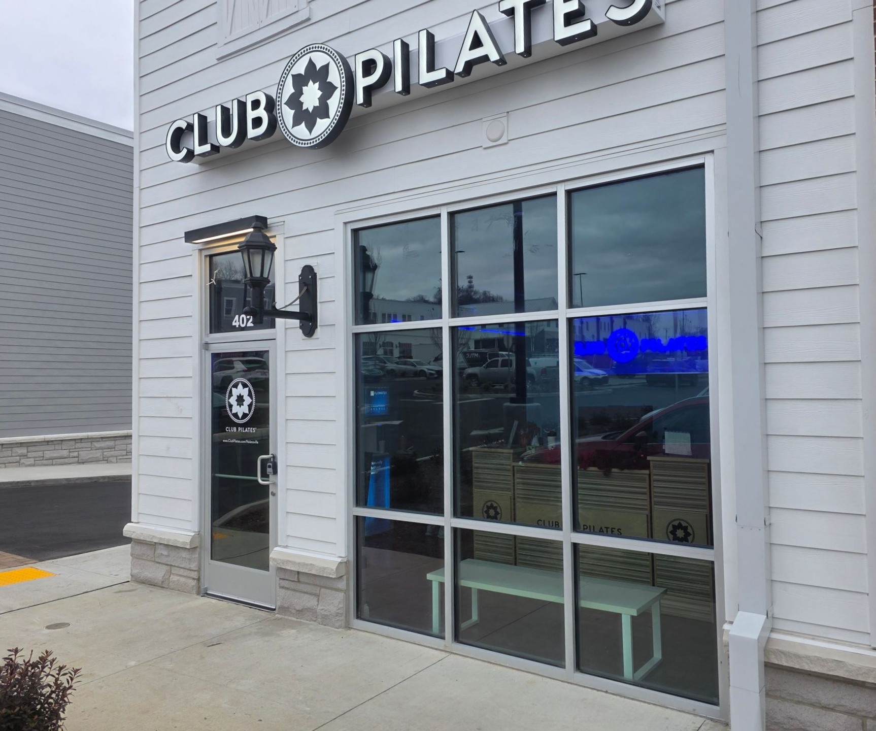 Club Pilates storefront with glass windows and black-and-white signage on a gray exterior.