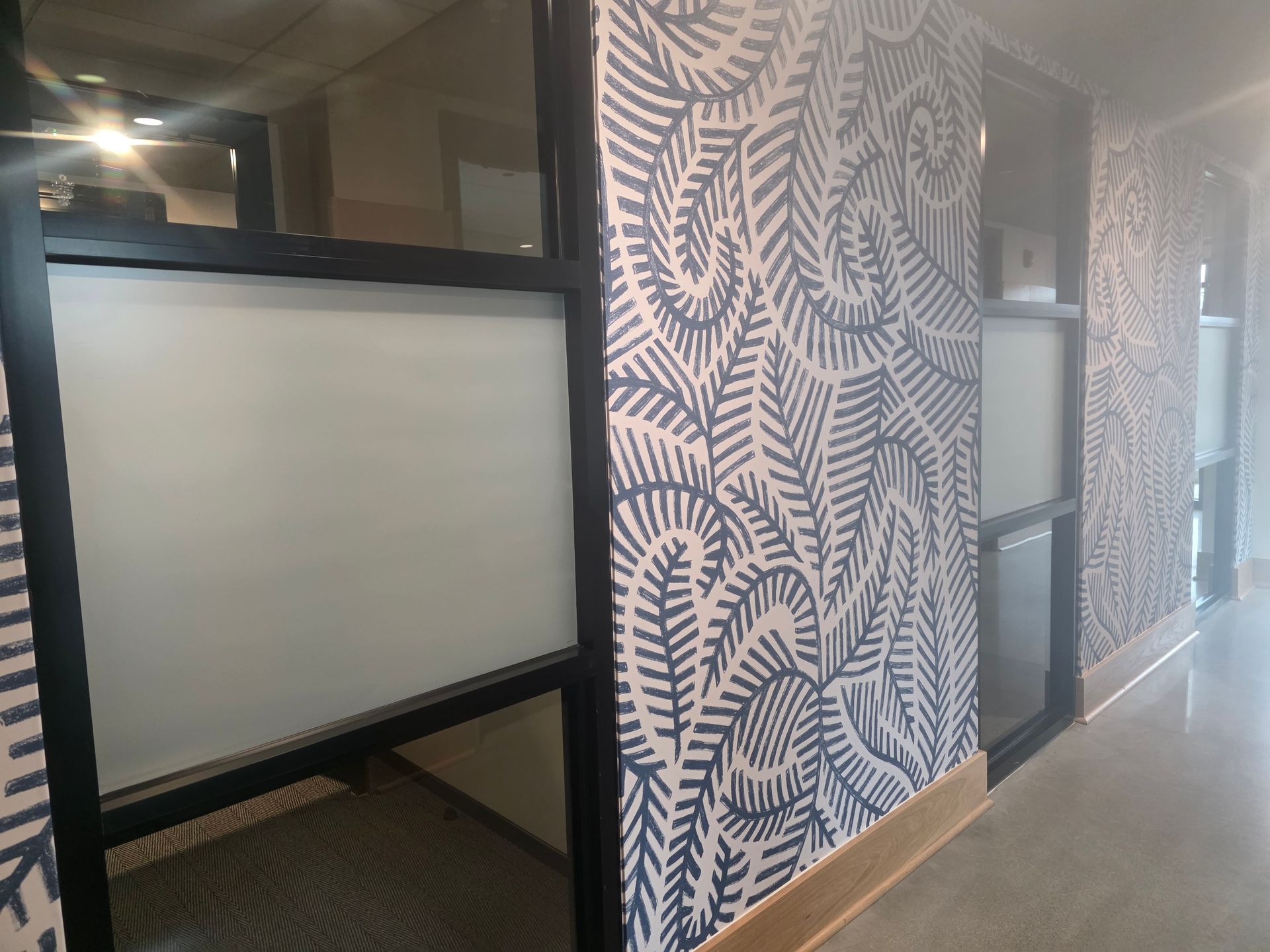 Office corridor with patterned walls and frosted glass cubicle partitions
