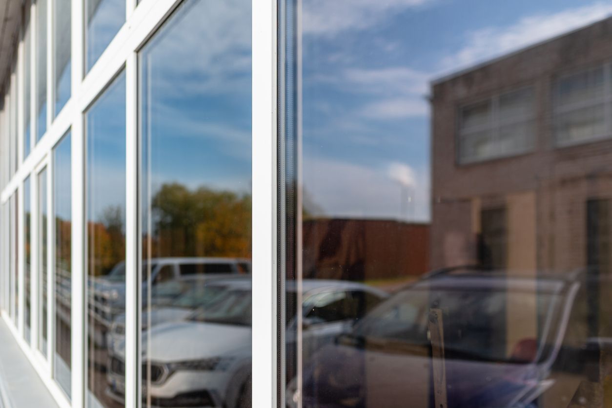 Storefront windows reflecting parked cars and a cloudy sky
