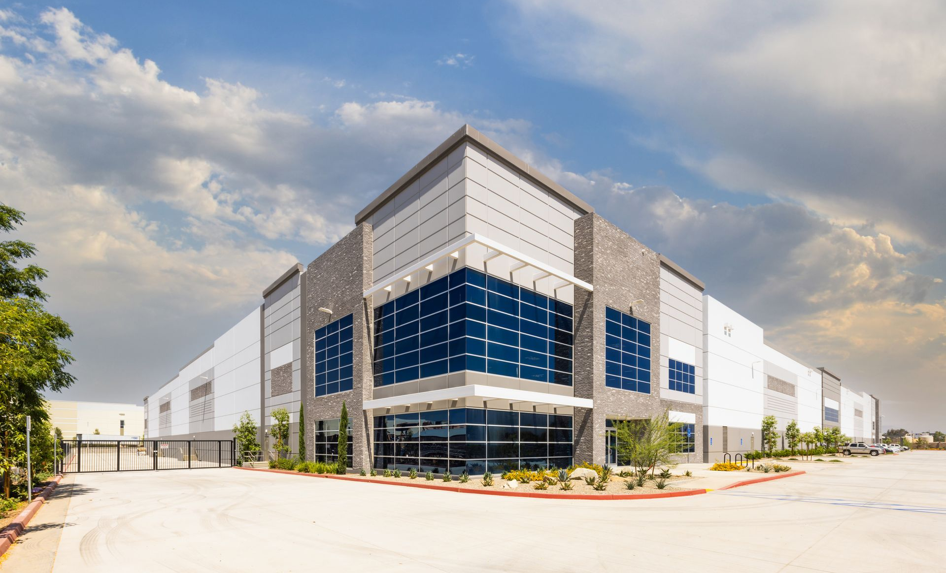 Modern industrial warehouse with white exterior and blue glass facade at a corner entrance