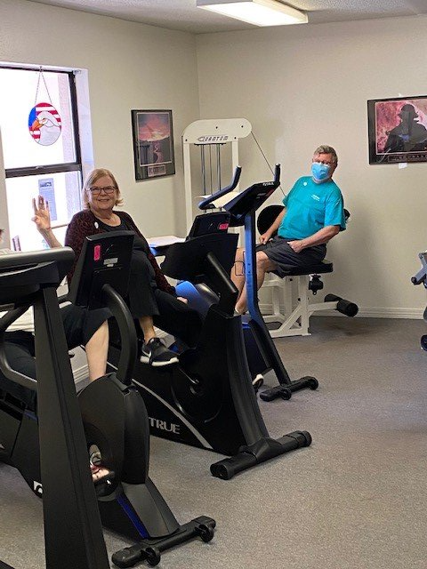 Small exercise room with two people using stationary bikes and cardio machines