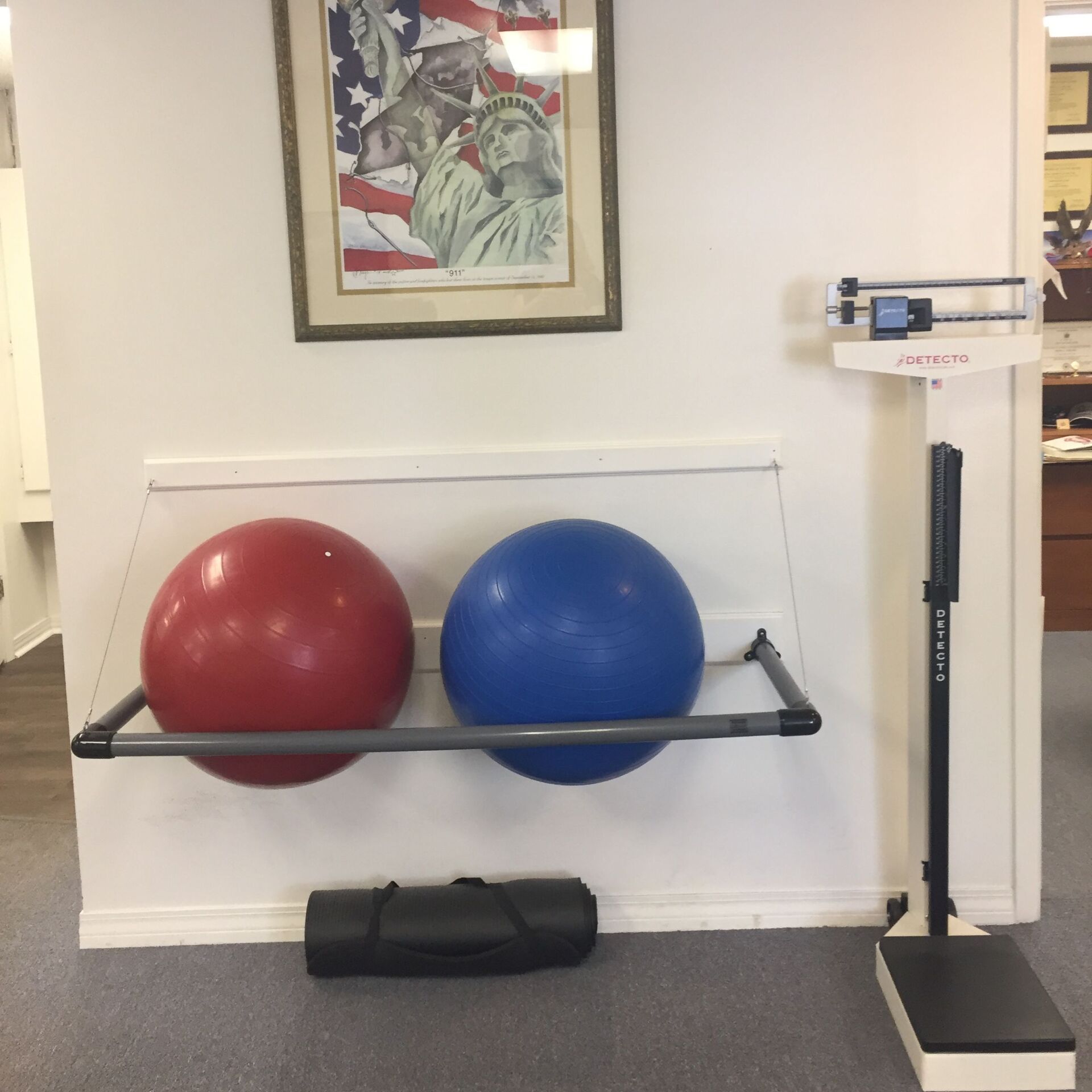 Two exercise balls, one red and one blue, resting on a shelf beside a weighing scale.