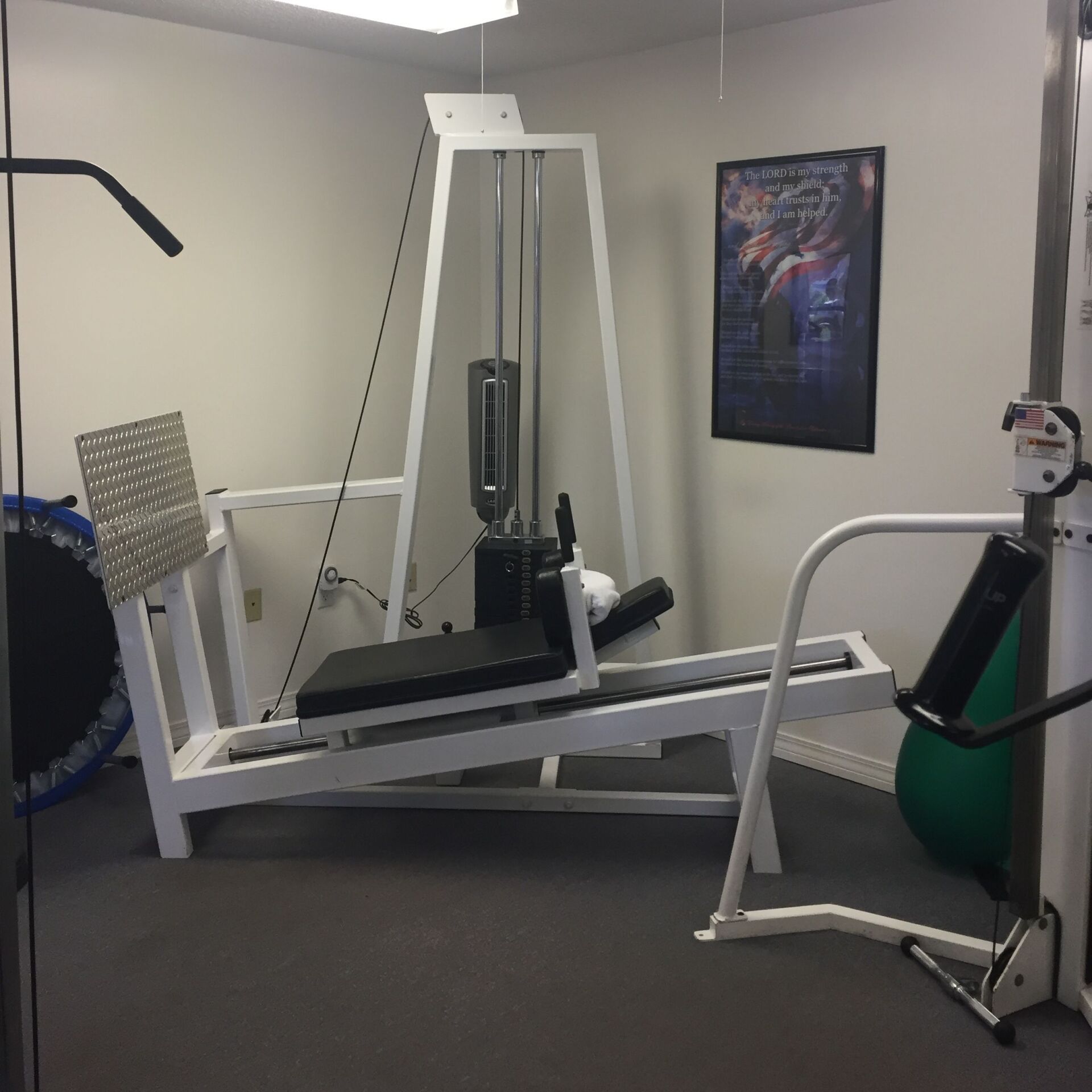 Small gym with cable exercise machine, bench, and weight equipment in a gray room