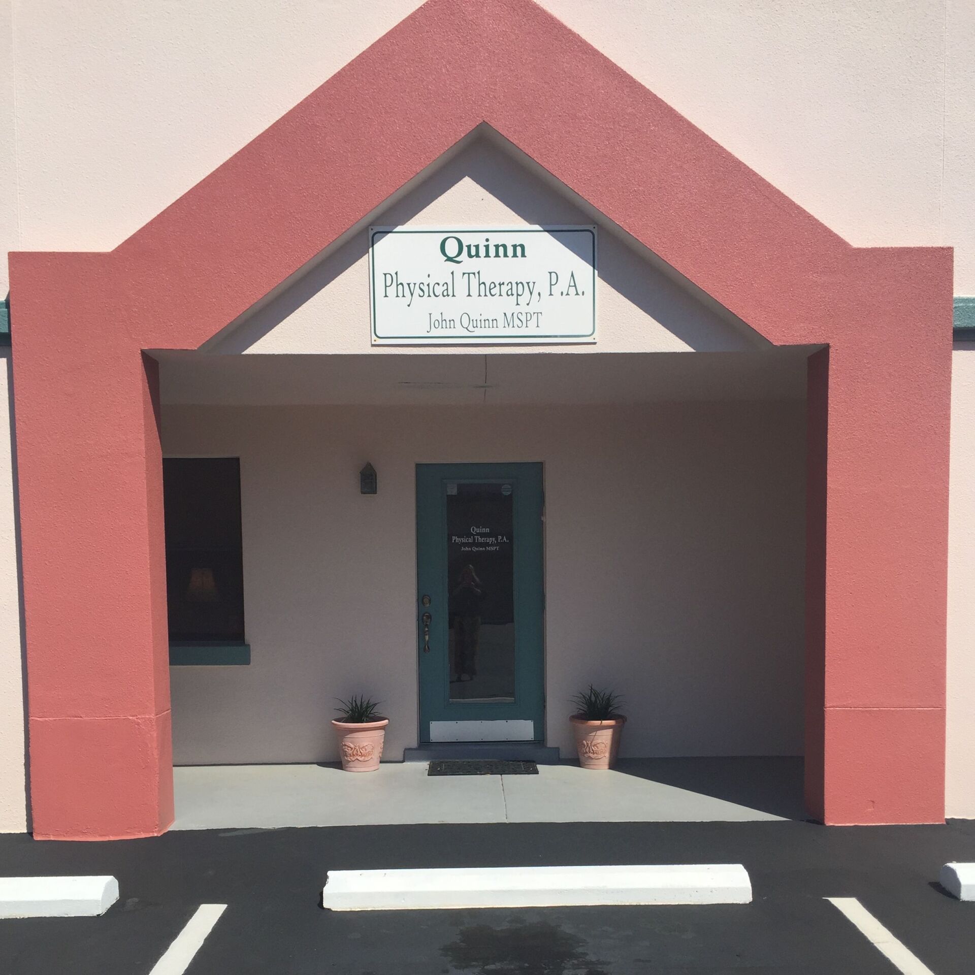 Front entrance of Quinn Physical Therapy, P.A., with red facade and covered doorway.
