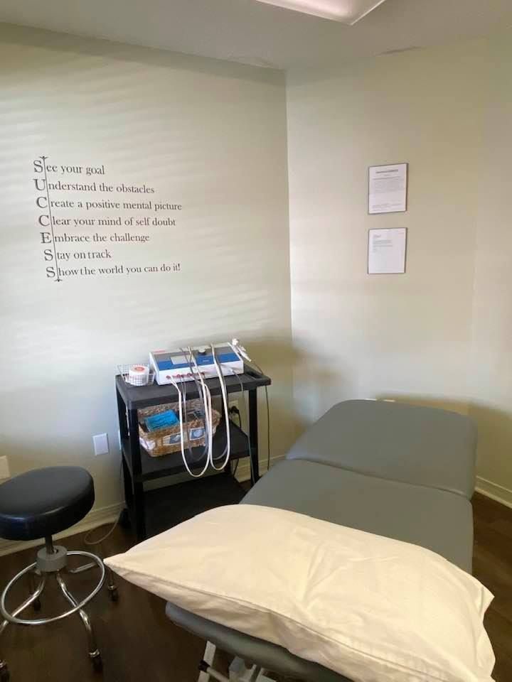 Medical exam room with exam table, stool, medical equipment cart, and wall notes