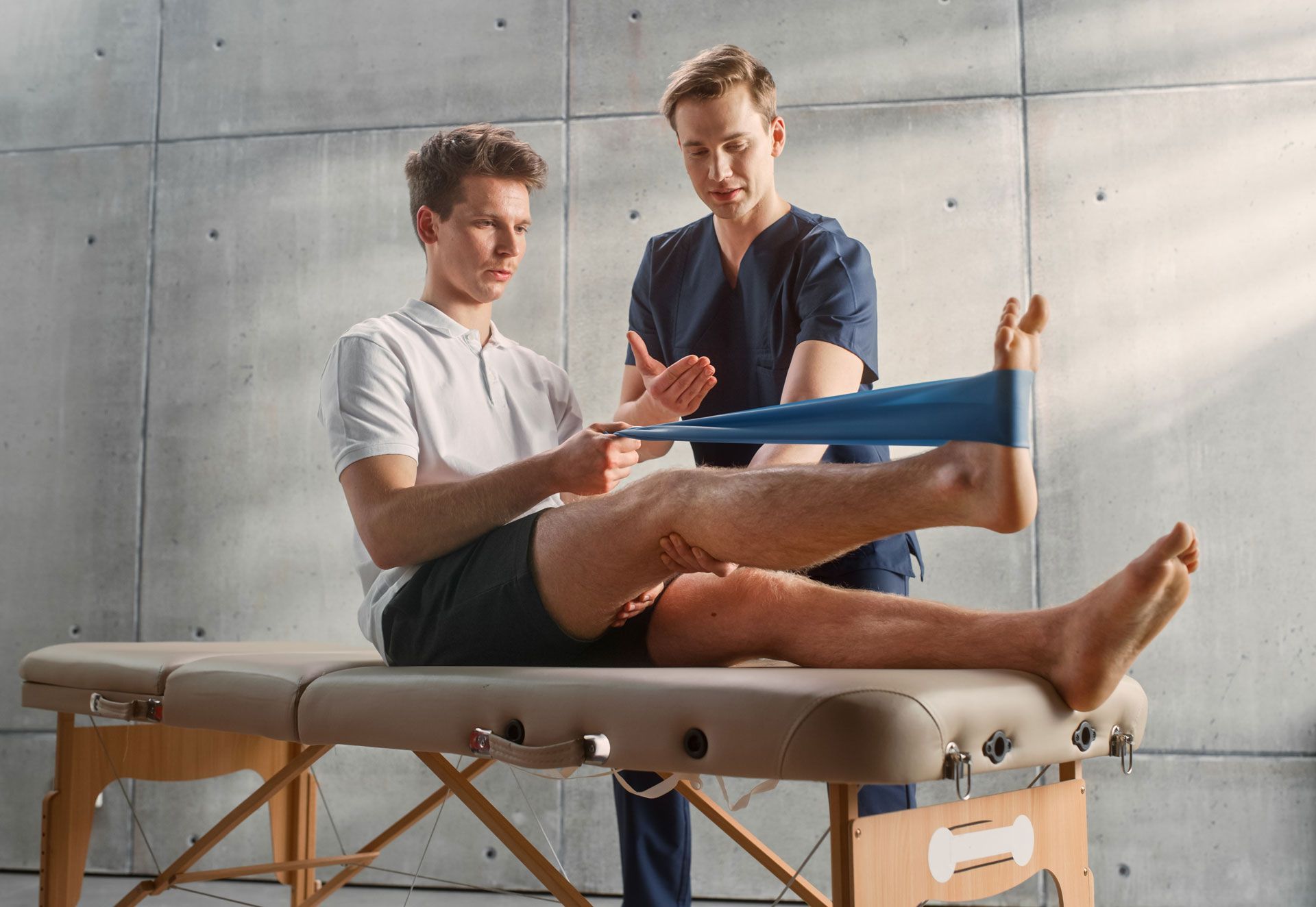 Physical therapist stretching a patient’s leg with a resistance band on a treatment table