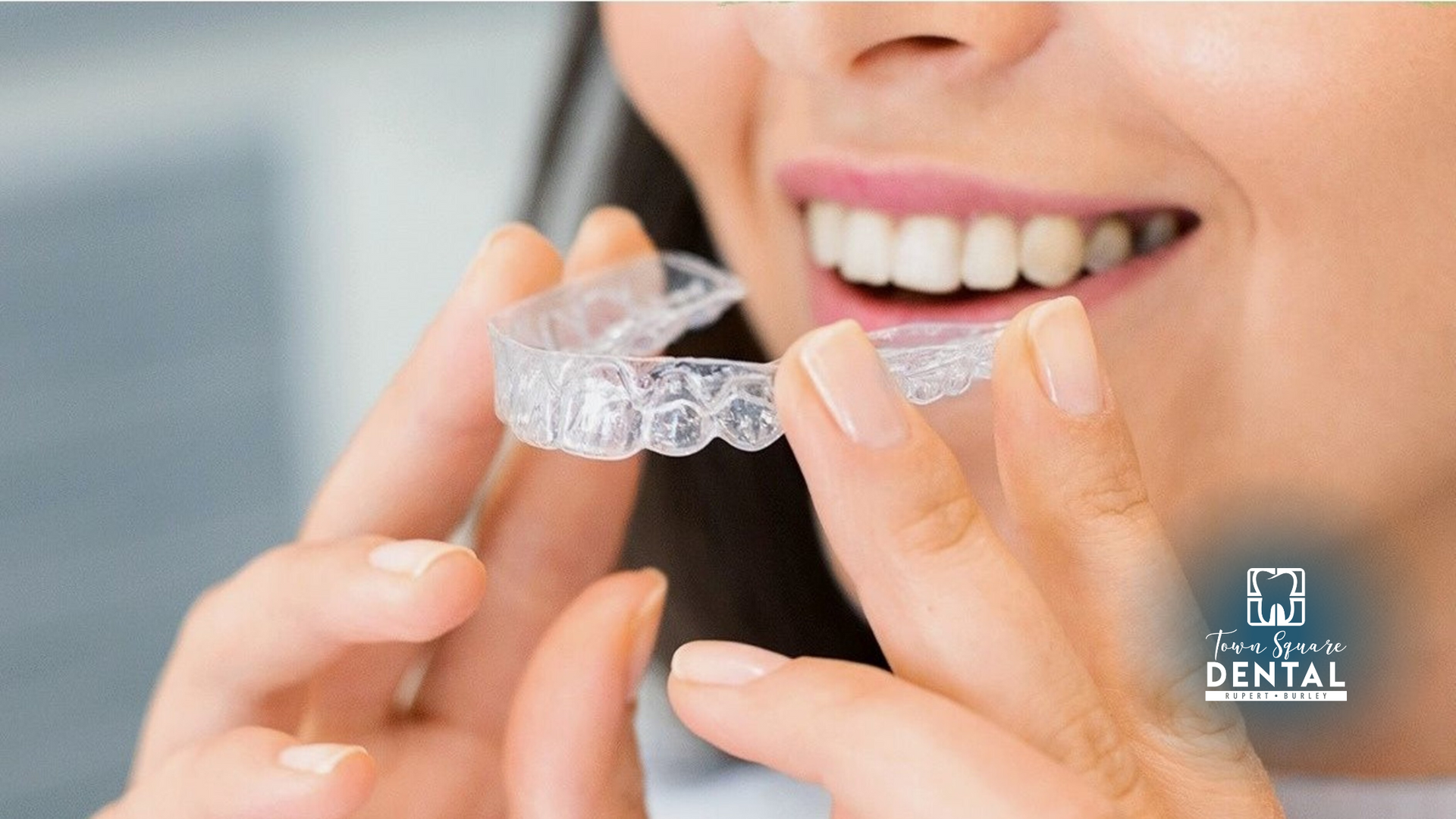 A woman is holding a clear brace in her mouth.