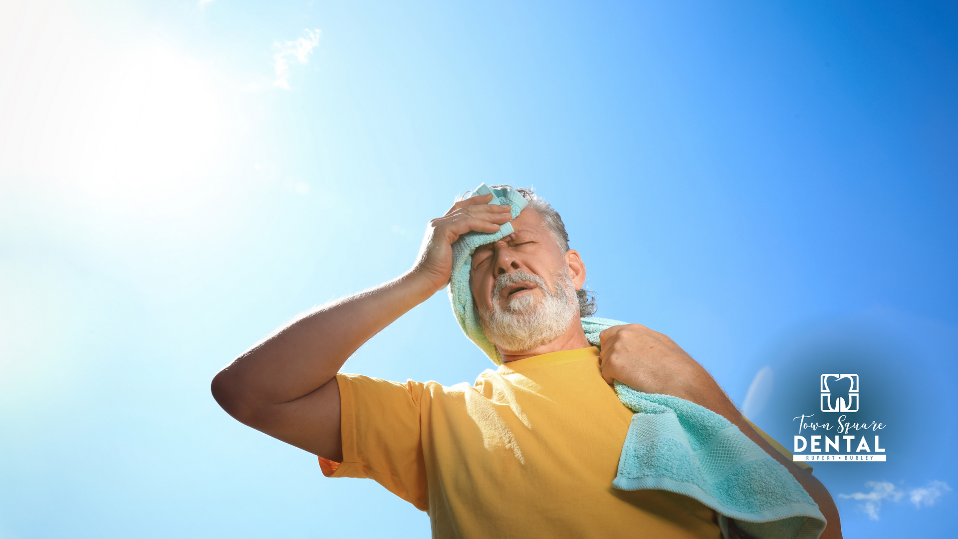 A man with a towel around his neck is sweating in the sun.