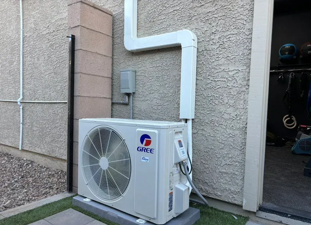 A white air conditioner is mounted on the side of a building.