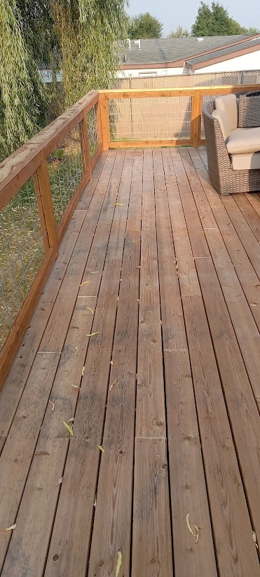 Wooden deck with railing. Outdoor setting with a couch.