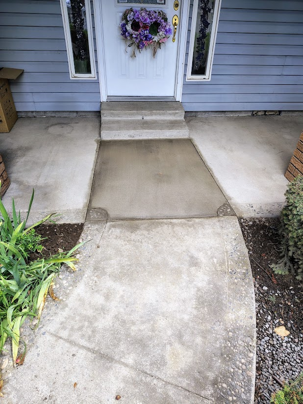 Concrete walkway leading to front door with steps and a purple wreath.