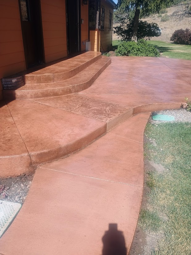 Orange concrete steps and walkway leading to a building's entrance. Green grass surrounds the walkway.