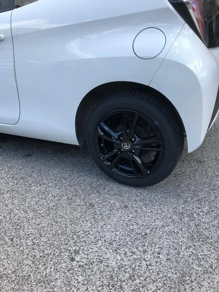 Un'auto bianca con uno pneumatico nero su una superficie di cemento.